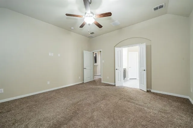 an empty room with windows and ceiling fan