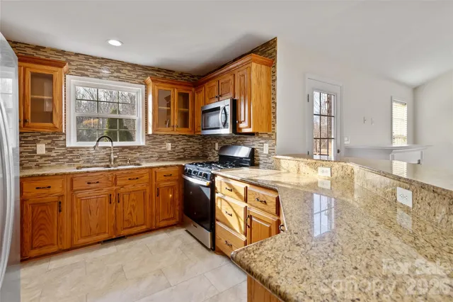 a kitchen with granite countertop a refrigerator stove top oven and sink