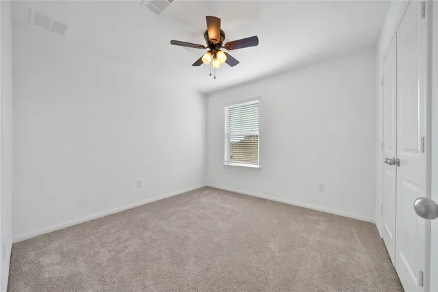 an empty room with ceiling fan and window