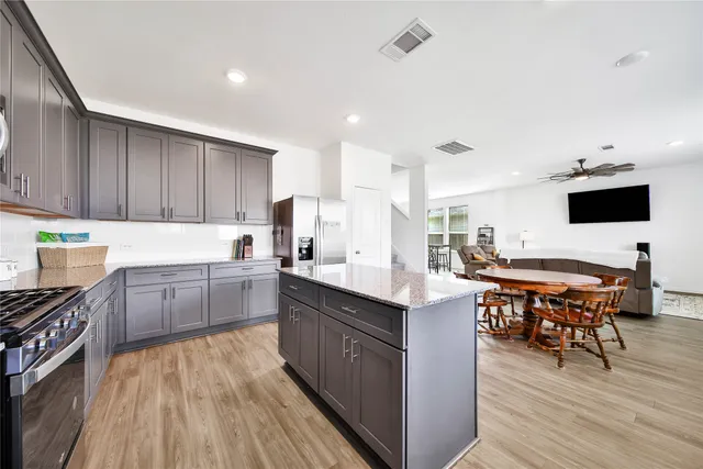 a kitchen with stainless steel appliances a stove top oven a sink dishwasher and a dining table with wooden floor