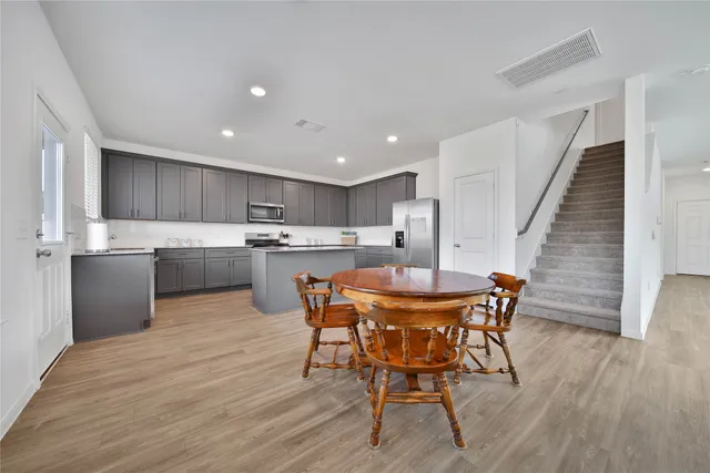 a kitchen with stainless steel appliances kitchen island wooden floors and chairs