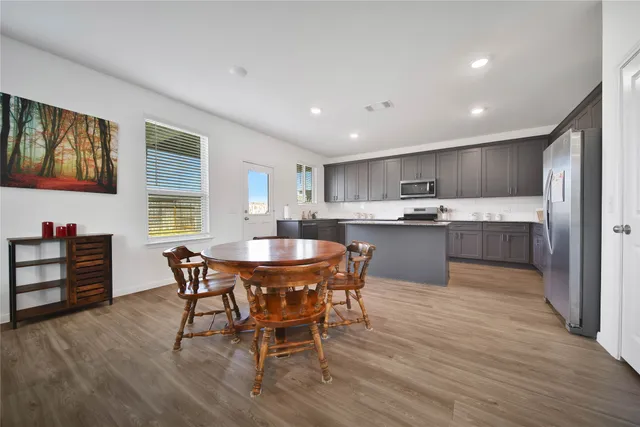 a kitchen with a dining table chairs and wooden floor