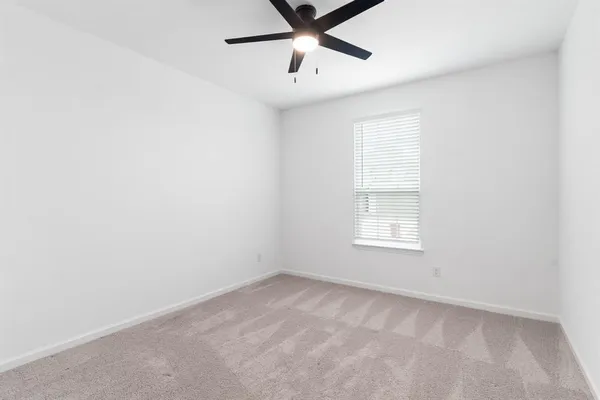 an empty room with a window and a fan