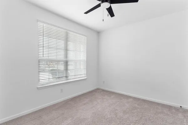 an empty room with a window and a ceiling fan