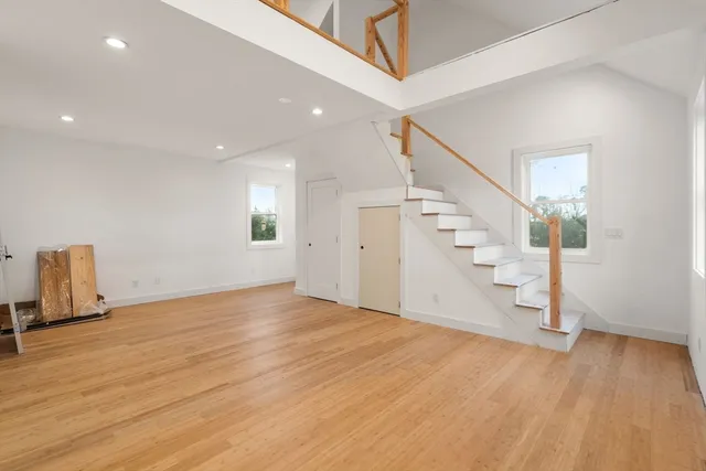 a view of an empty room with wooden floor and stairs