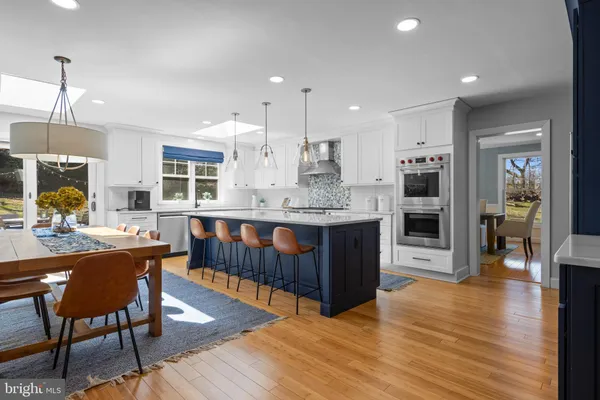a kitchen with stainless steel appliances granite countertop a stove a sink dishwasher and a dining table with wooden floor