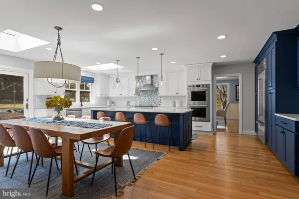 a large kitchen with stainless steel appliances kitchen island granite countertop a table chairs and a refrigerator