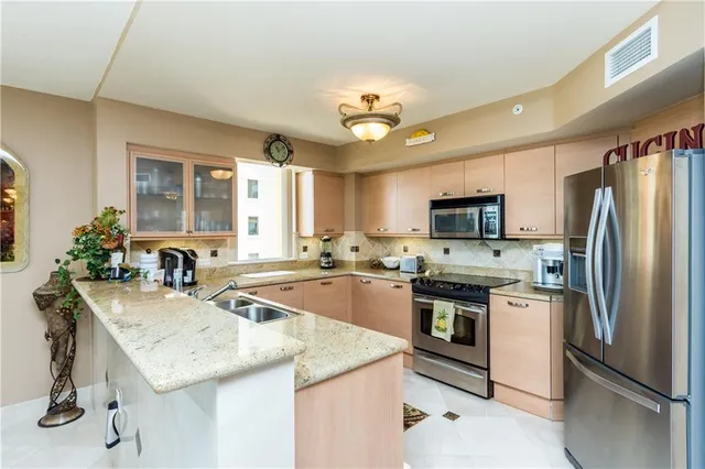 a kitchen with stainless steel appliances granite countertop a sink stove microwave and refrigerator