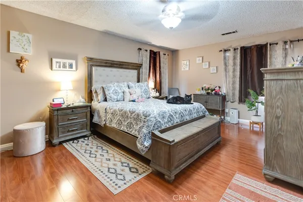 a bedroom with a bed and a dresser with wooden floor