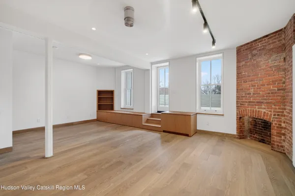 a view of an empty room with wooden floor and fireplace