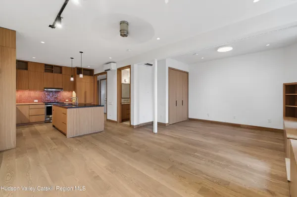 a view of an empty room with kitchen and a window