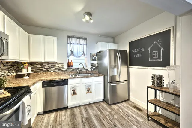 a kitchen with stainless steel appliances white cabinets and a stove top oven