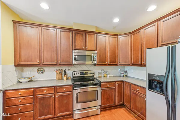 a kitchen with stainless steel appliances granite countertop a refrigerator a sink dishwasher stove with cabinets