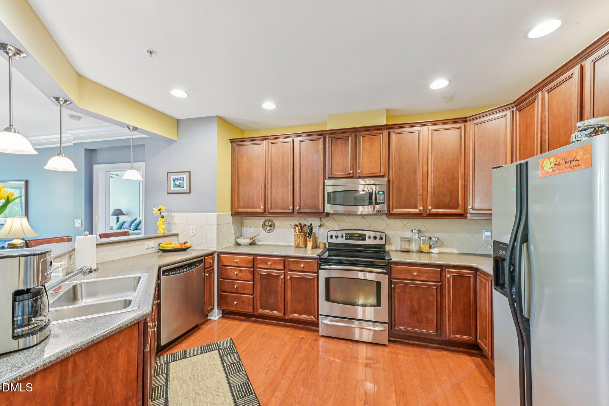10411 Rosegate Court, Unit 205 Raleigh, NC 27617 - Photo 7 of 38 a kitchen with stainless steel appliances granite countertop a stove top oven a sink dishwasher a refrigerator and cabinets with wooden floor