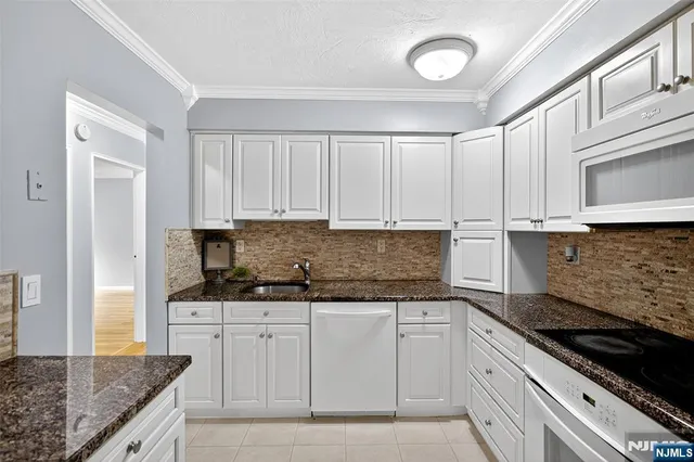 a kitchen with granite countertop a sink stainless steel appliances and white cabinets
