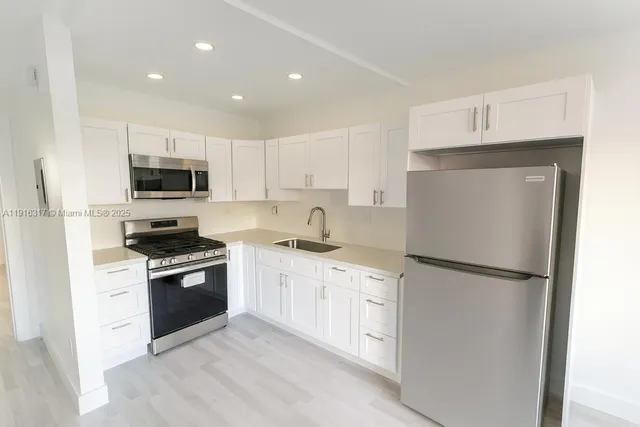 a kitchen with white cabinets and stainless steel appliances