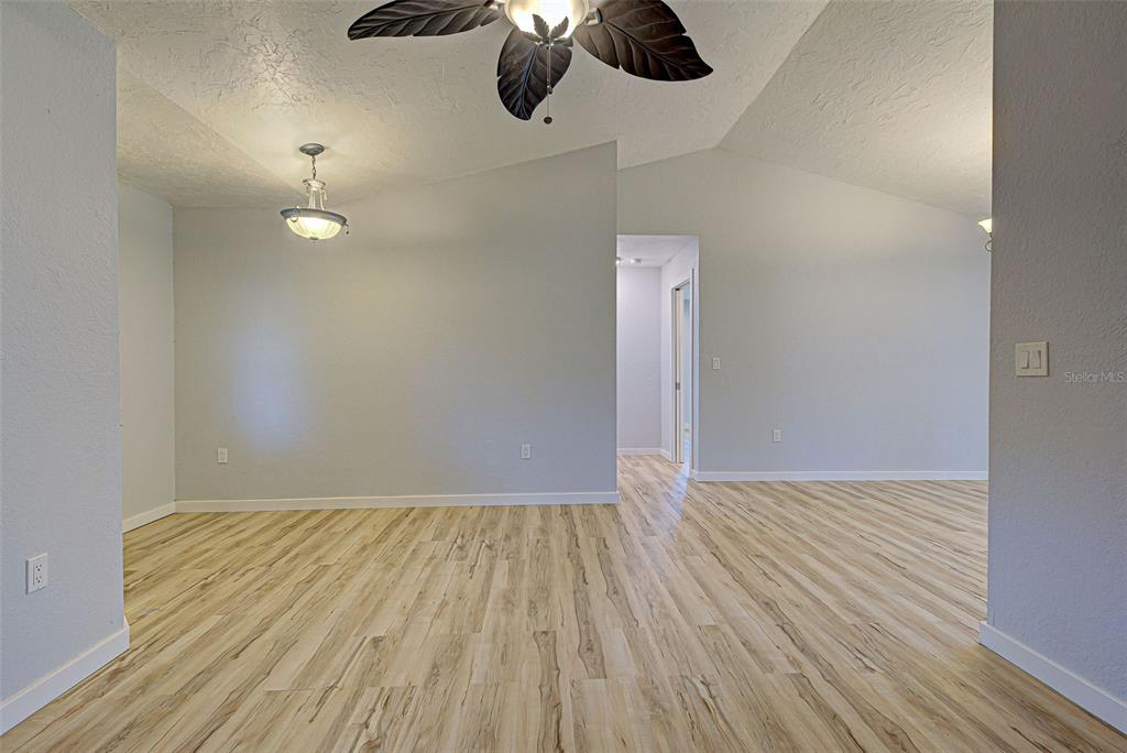 3187 Galiot Road Venice, FL 34293 - Photo 8 of 46 a view of an empty room with chandelier fan and wooden floor