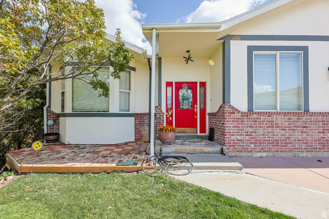569 Elk Meadow Loop Tooele, UT 84074 - Photo 2 of 56 Property entrance with stucco siding, a lawn, and brick siding