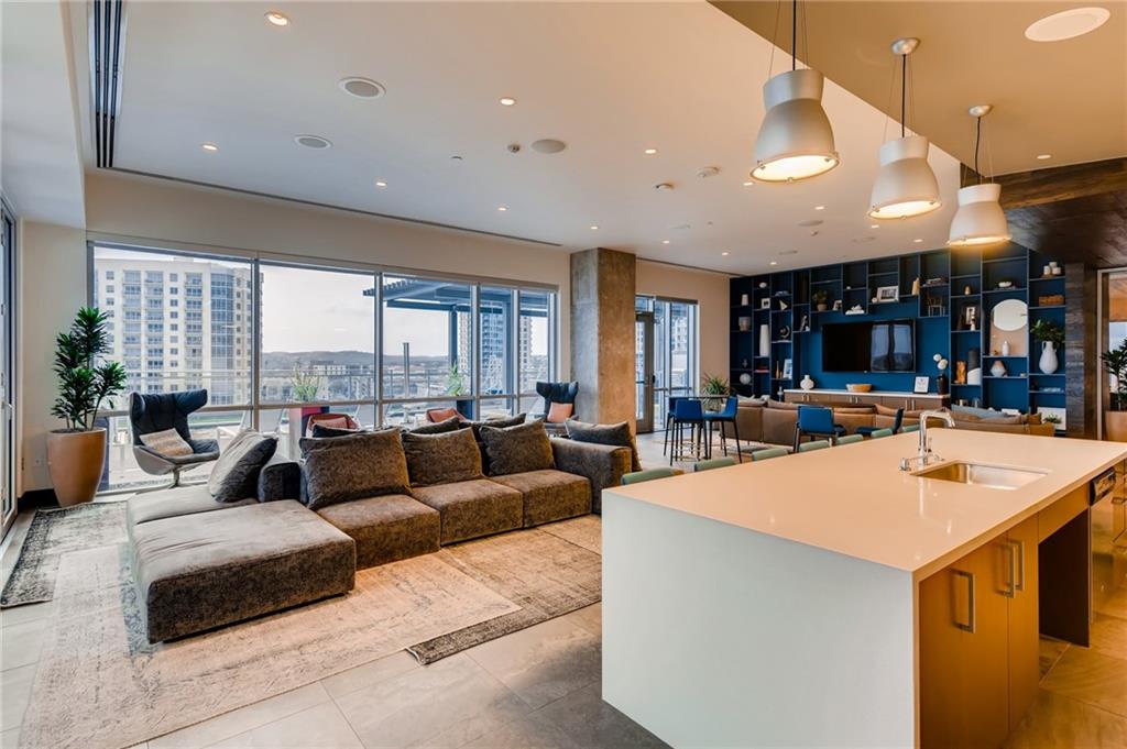 222 West Avenue, Unit 2207 Austin, TX 78701 - Photo 28 of 30 Open-concept living space with expansive window walls, a large kitchen island with integrated sink, recessed lighting, and built-in shelving