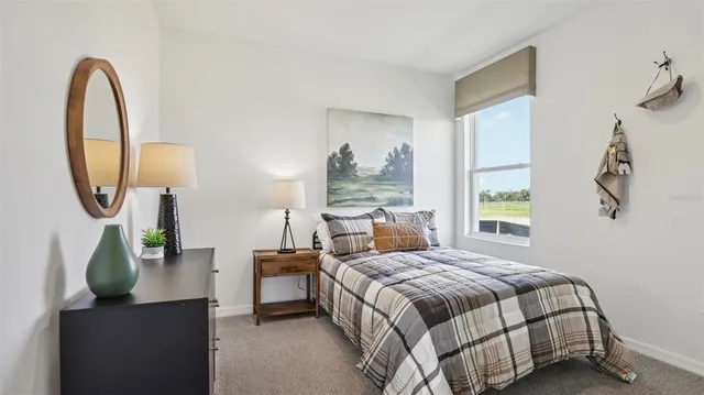 a bedroom with a bed a mirror and a potted plant next to a window