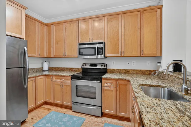 a kitchen with granite countertop a sink stainless steel appliances and cabinets