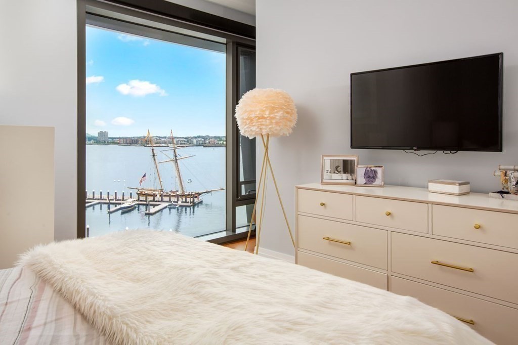 300 Pier 4 Blvd., Unit 8N Boston, MA 02210 - Photo 20 of 37 a bedroom with a bed and a flat tv screen on dresser