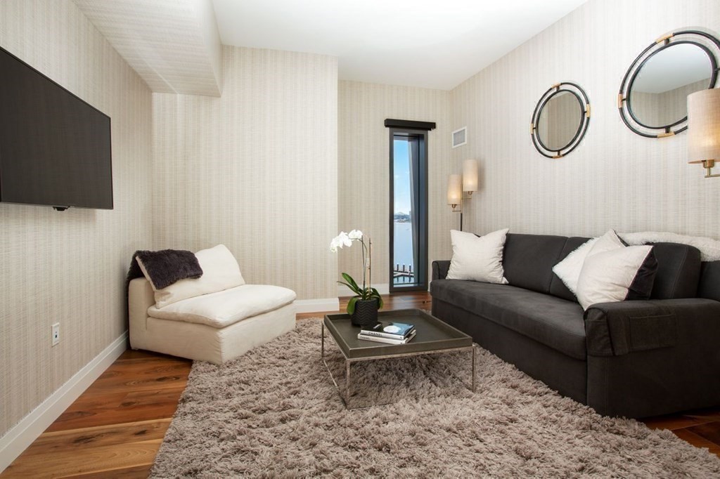 300 Pier 4 Blvd., Unit 8N Boston, MA 02210 - Photo 23 of 37 a living room with furniture a flat screen tv and a rug