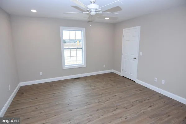 an empty room with wooden floor window and ceiling fan