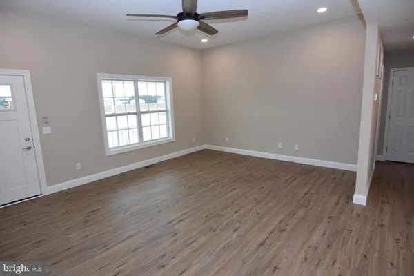 an empty room with wooden floor fan and windows