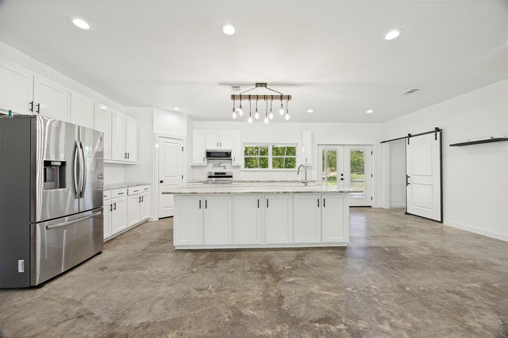 822 Private Road 7370 Point, TX 75472 - Photo 15 of 30 Open-concept kitchen featuring an expansive center island, white cabinetry, integrated stainless steel appliances, and concrete-finish flooring