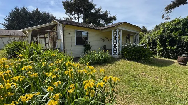 a view of a white house with a yard and plants