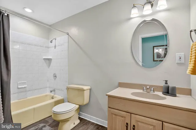 a bathroom with a toilet sink vanity granite tub and shower