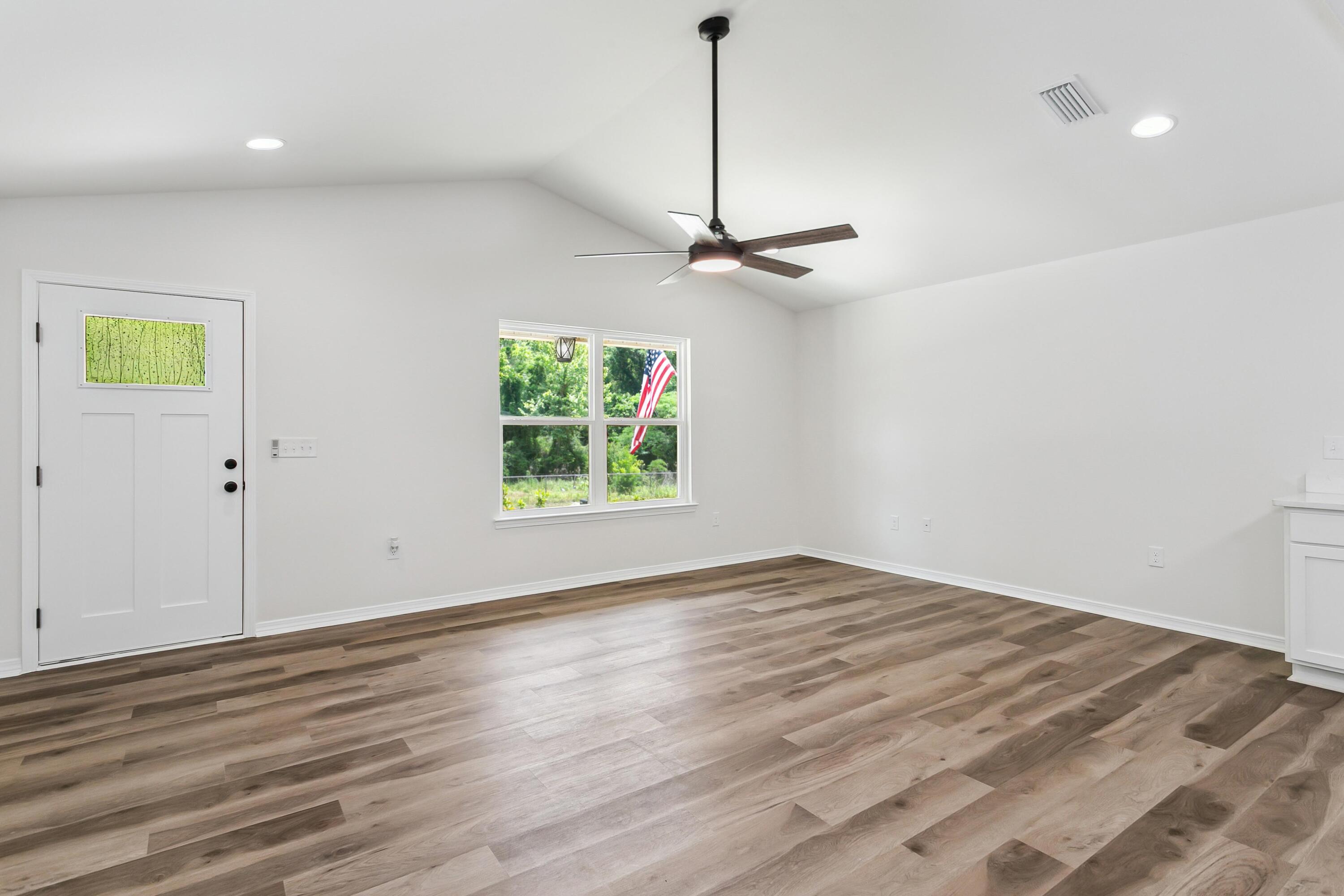 8084 3rd Street Laurel Hill, FL 32567 - Photo 7 of 34 a view of an empty room with a window and wooden floor