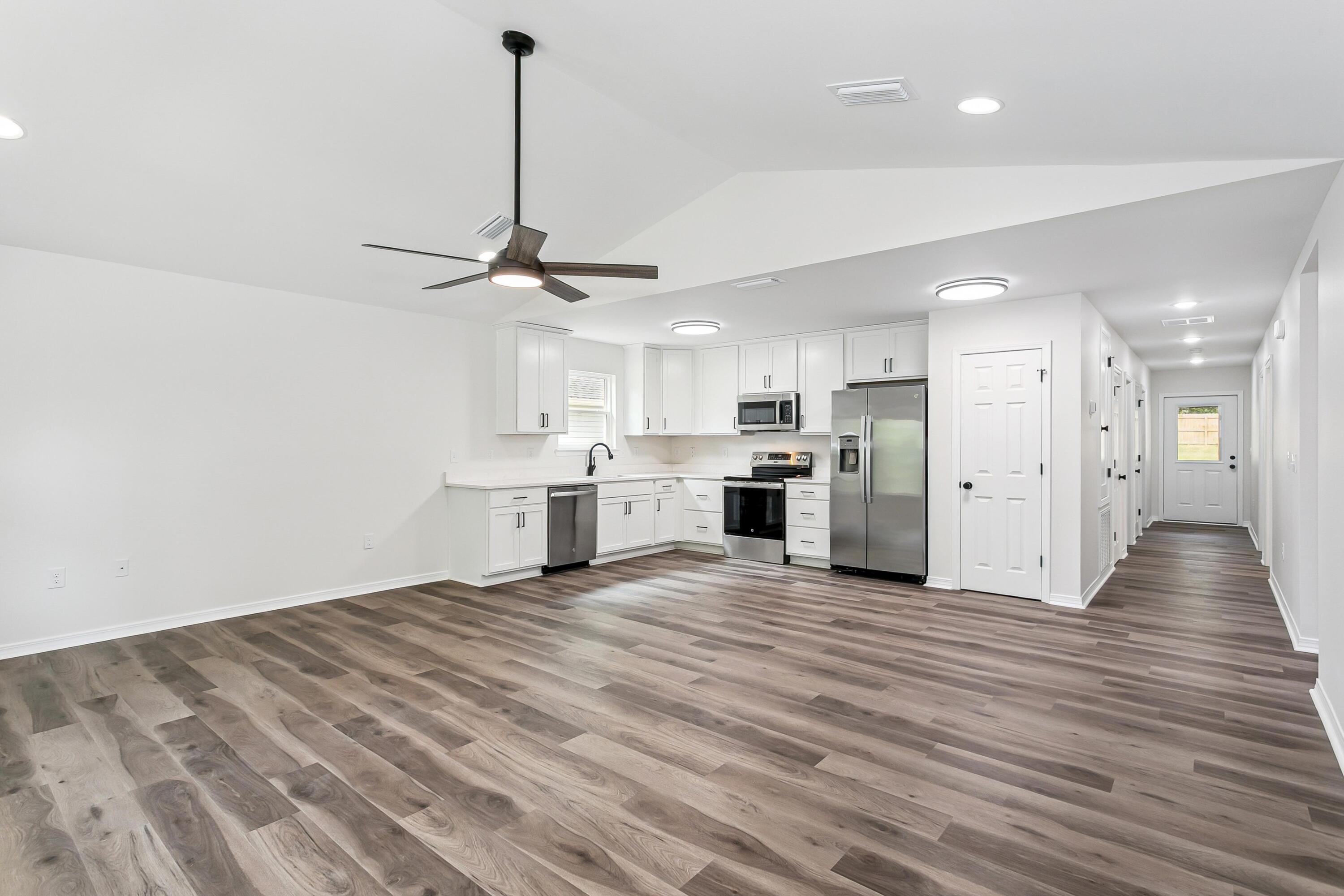 8084 3rd Street Laurel Hill, FL 32567 - Photo 8 of 34 a view of a kitchen with a stove wooden cabinet wooden floor and a chandelier