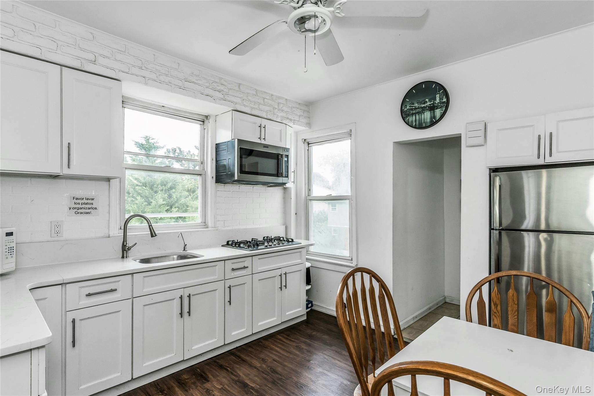 91-15 79th Street Queens, NY 11421 - Photo 9 of 12 a kitchen with a sink a window and a clock on the wall