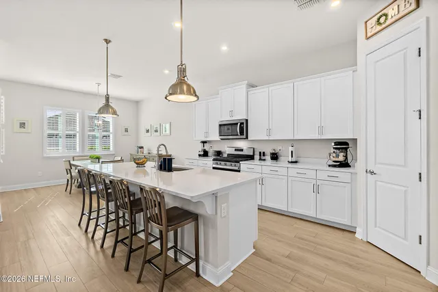 a kitchen with stainless steel appliances granite countertop a sink a stove a refrigerator and white cabinets with wooden floor