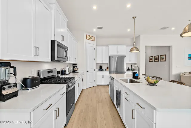 a large white kitchen with stainless steel appliances granite countertop a sink a stove and a refrigerator