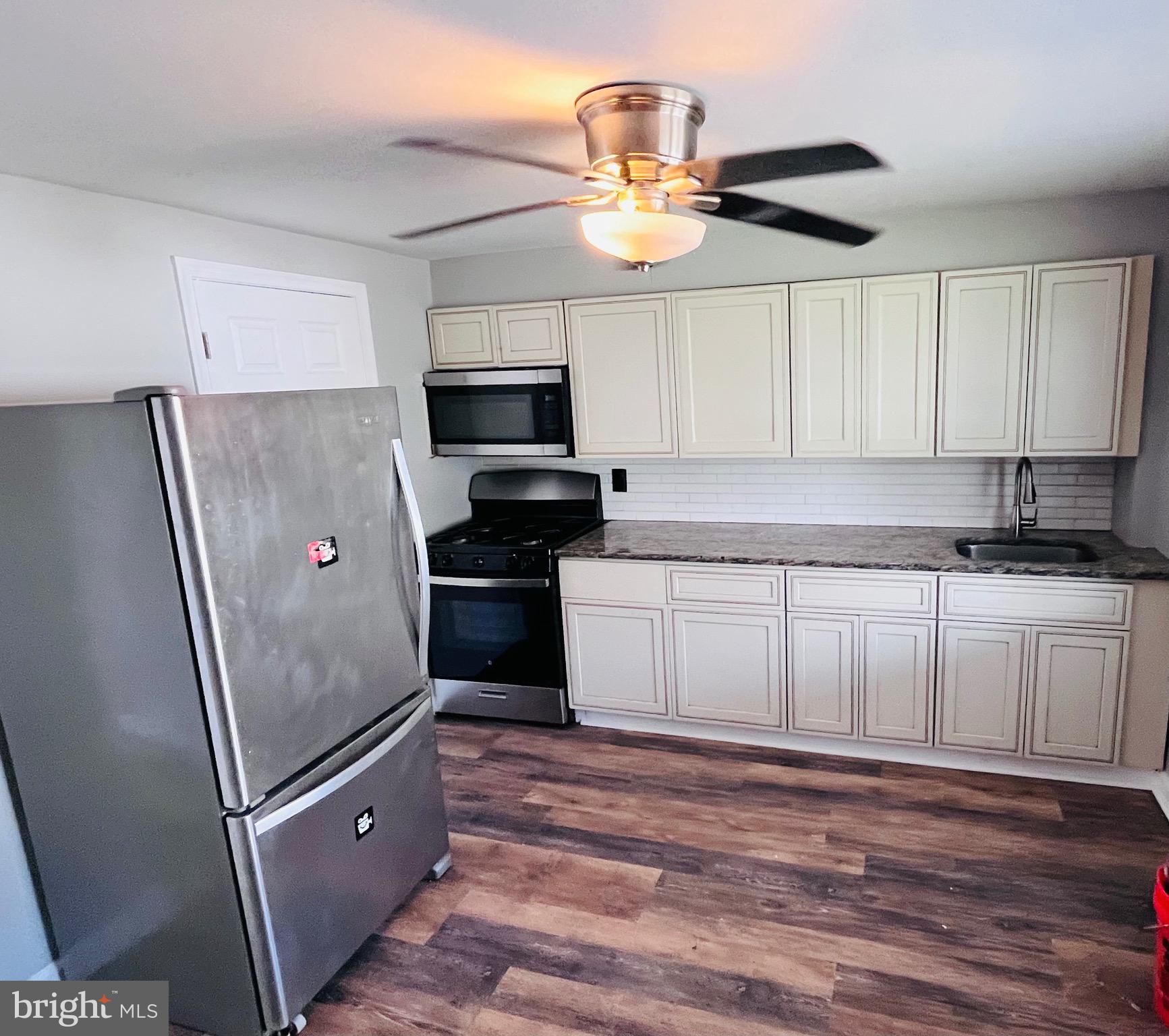 7932 Wynbrook Road Baltimore, MD 21224 - Photo 5 of 13 a kitchen with stainless steel appliances granite countertop a refrigerator a stove a sink and white cabinets