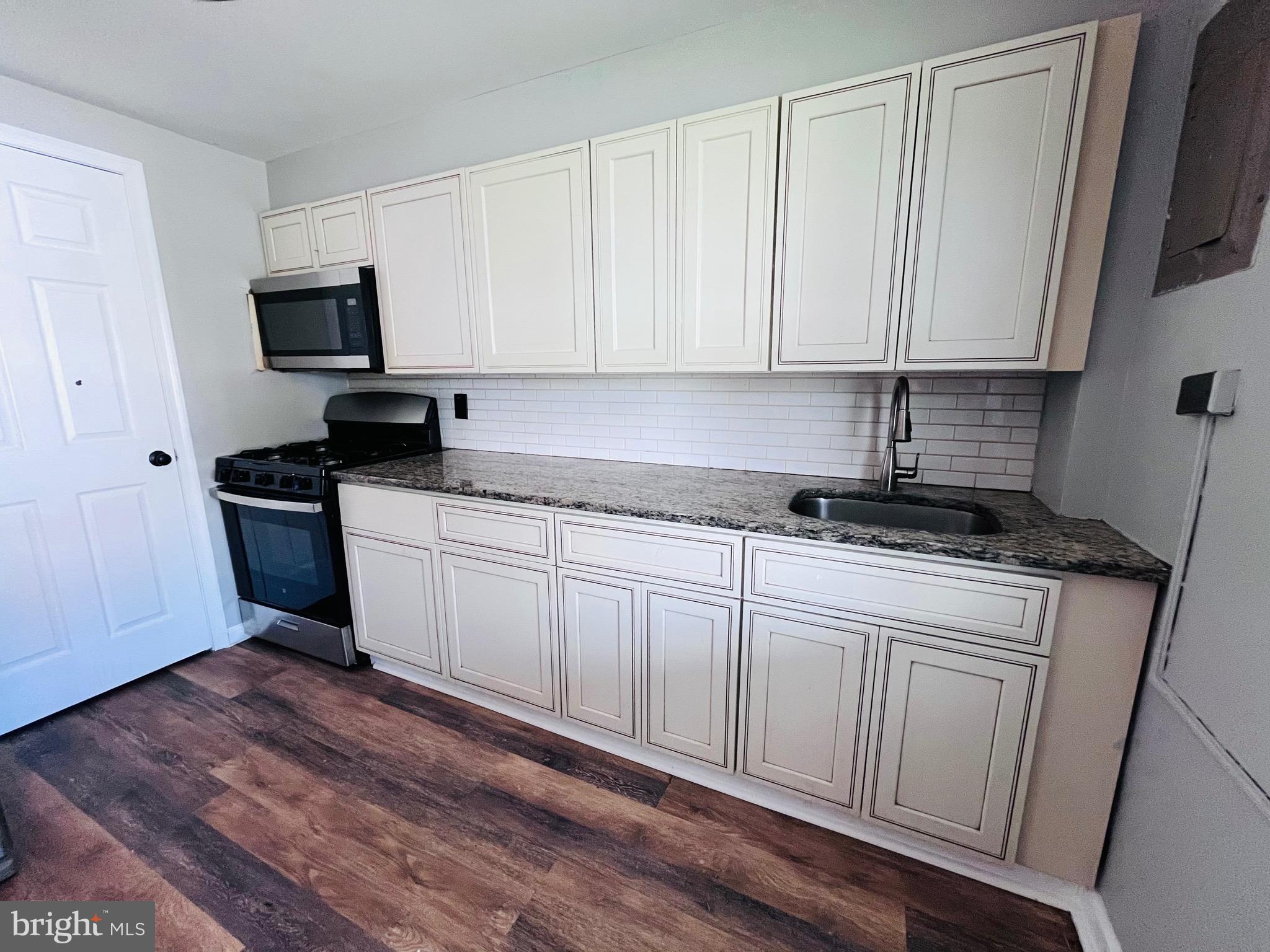7932 Wynbrook Road Baltimore, MD 21224 - Photo 6 of 13 a kitchen with granite countertop white cabinets sink and stainless steel appliances