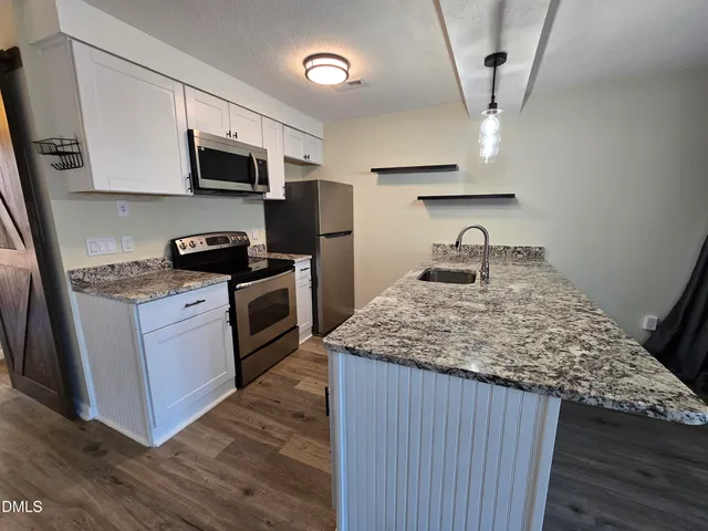 a kitchen with stainless steel appliances granite countertop a sink stove and microwave