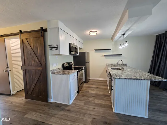 a kitchen with kitchen island granite countertop wooden floors and a sink