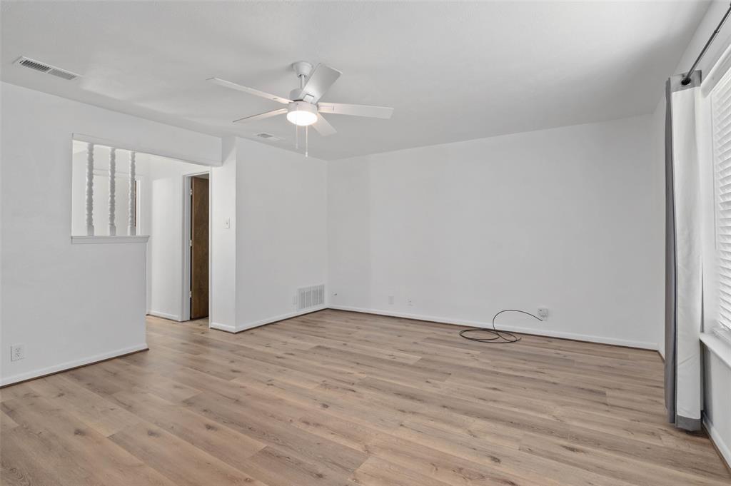 301 East 6th Street Krum, TX 76249 - Photo 8 of 29 Huge primary bedroom with wood-like flooring, ceiling fan and en-suite bathroom.