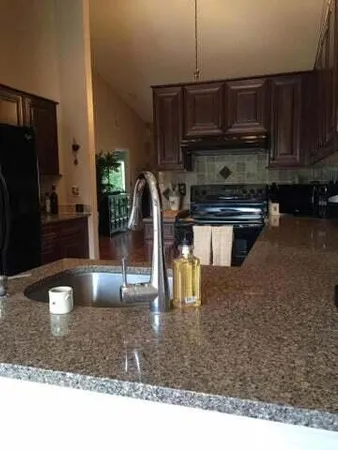 a kitchen with kitchen island granite countertop a stove a sink and a microwave