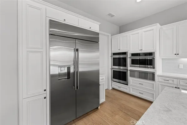 a kitchen with granite countertop a stove a sink and white cabinets