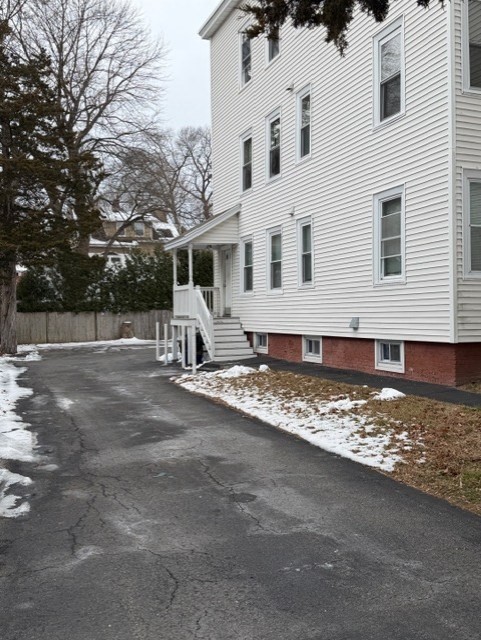 21 Sylvan Street, Unit 1 Worcester, MA 01603 - Photo 10 of 10 a view of a white house with a yard covered with snow and trees