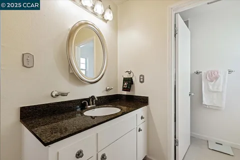 a bathroom with a granite countertop sink and a mirror