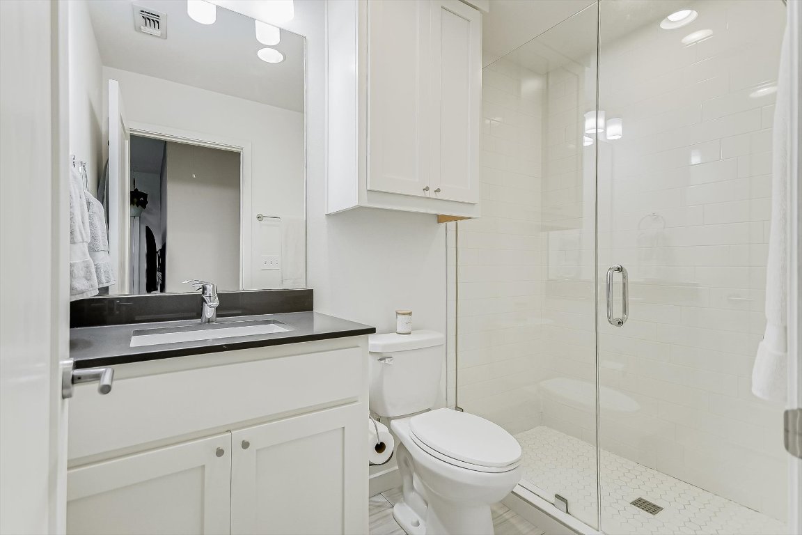 2414 East Martin Luther King Jr Boulevard, Unit A Austin, TX 78722 - Photo 23 of 32 a bathroom with a granite countertop sink a toilet and a mirror