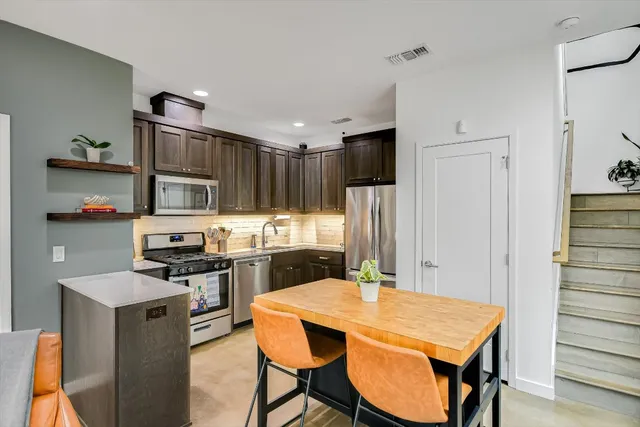 a kitchen with stainless steel appliances a stove a refrigerator and a dining table