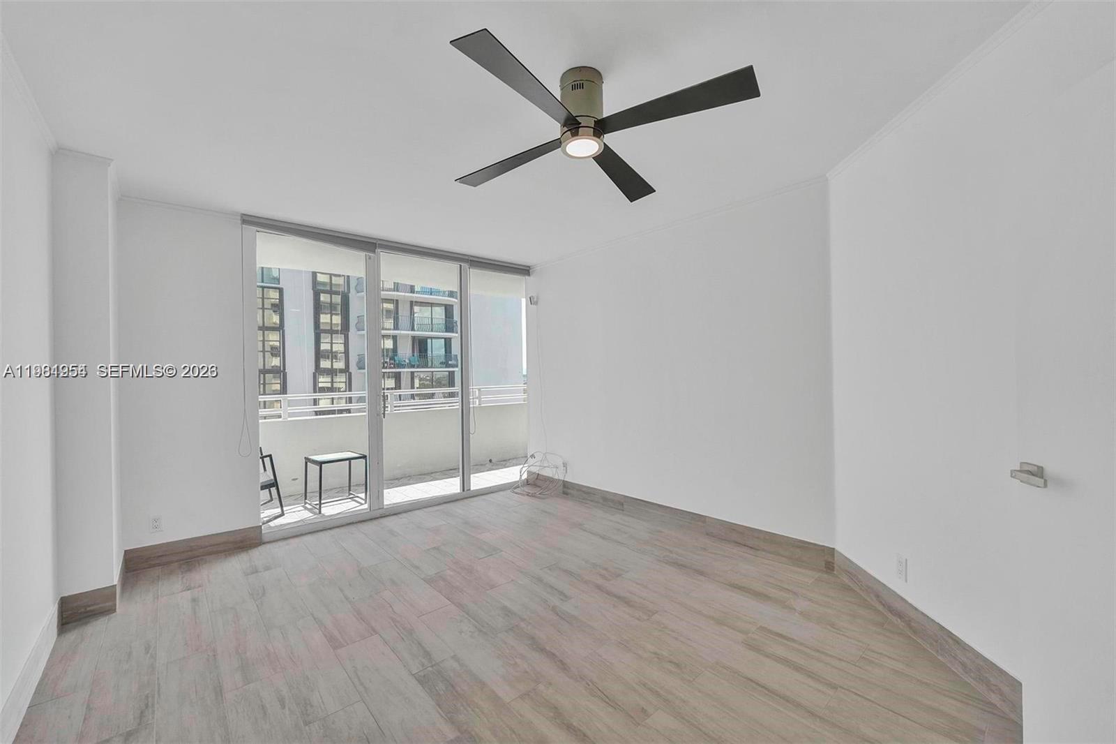 8911 Collins Avenue, Unit 703 Surfside, FL 33154 - Photo 12 of 24 an empty room with wooden floor and a ceiling fan