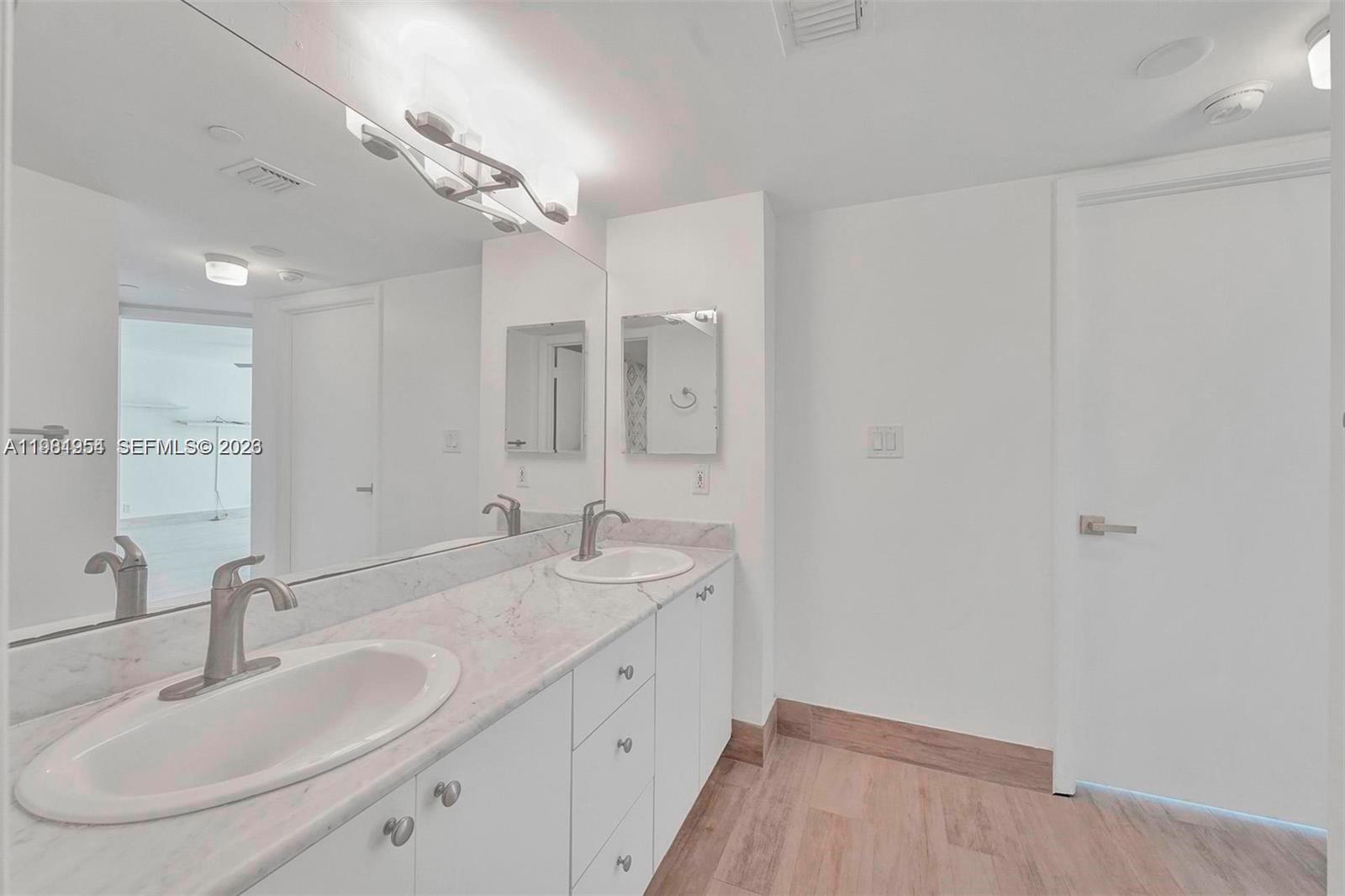 8911 Collins Avenue, Unit 703 Surfside, FL 33154 - Photo 18 of 24 a bathroom with a double vanity sink and a mirror